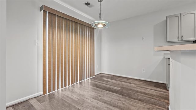 unfurnished dining area with wood finished floors, visible vents, and baseboards