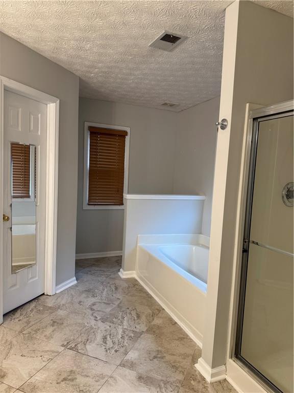 bathroom with independent shower and bath and a textured ceiling