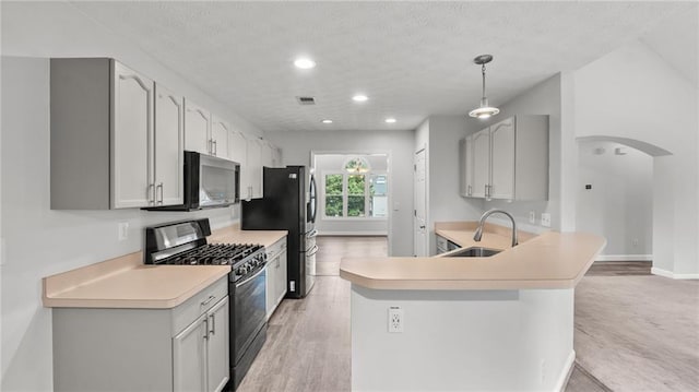 kitchen featuring arched walkways, stainless steel appliances, a sink, visible vents, and light wood-style floors