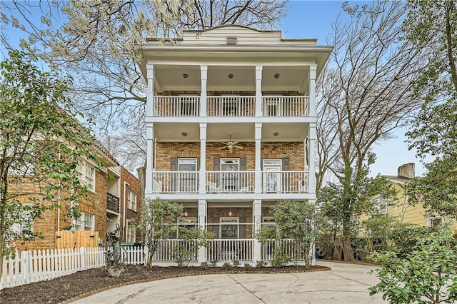 view of front of property featuring a balcony, fence, and brick siding