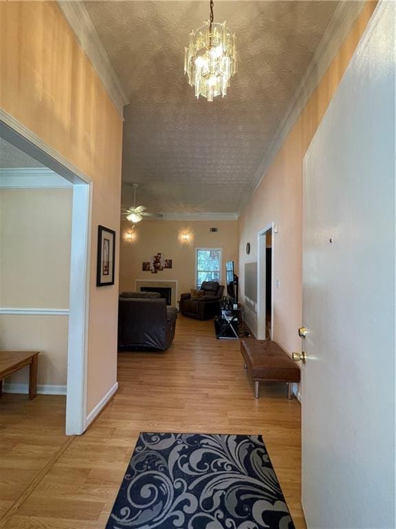 corridor with crown molding, light hardwood / wood-style flooring, and a chandelier