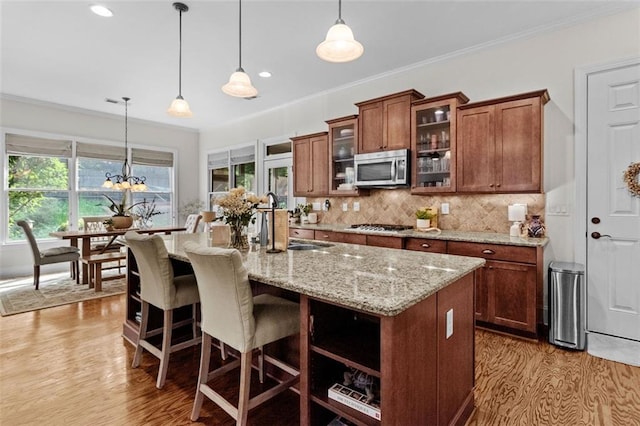 1771 Silvergrass Ln, Grayson, GA 30017 - kitchen featuring appliances with stainless steel finishes, light wood finished floors, light stone counters, decorative backsplash, and crown molding