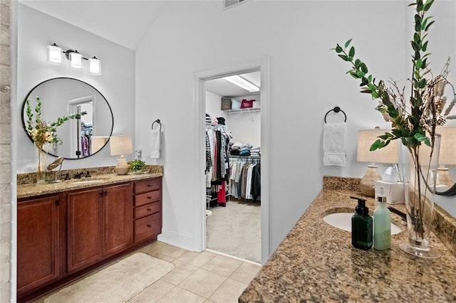 1771 Silvergrass Ln, Grayson, GA 30017 - bathroom with two vanities, tile patterned flooring, lofted ceiling, and a walk in closet