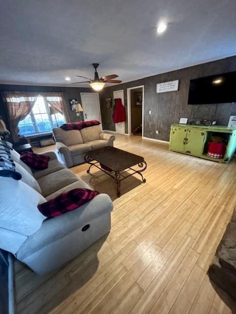 living room featuring ceiling fan, wooden walls, and hardwood / wood-style floors