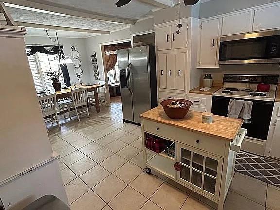 kitchen featuring beamed ceiling, appliances with stainless steel finishes, white cabinets, and ceiling fan