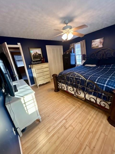 bedroom featuring a textured ceiling, ceiling fan, and light wood-type flooring