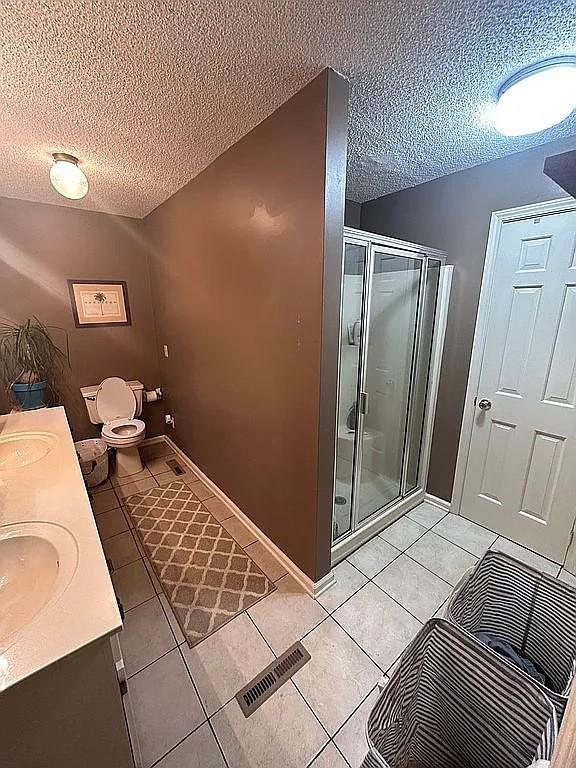 bathroom with tile patterned flooring, vanity, toilet, and walk in shower