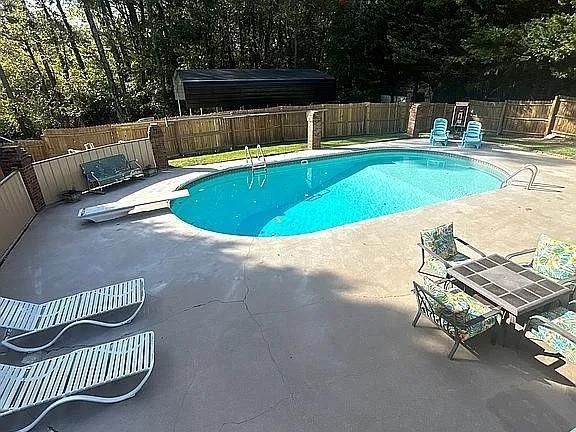 view of pool featuring a diving board and a patio