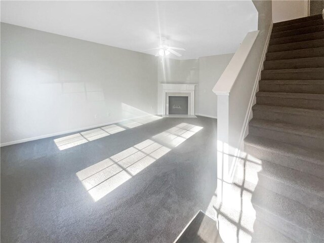 unfurnished room with ceiling fan and dark colored carpet