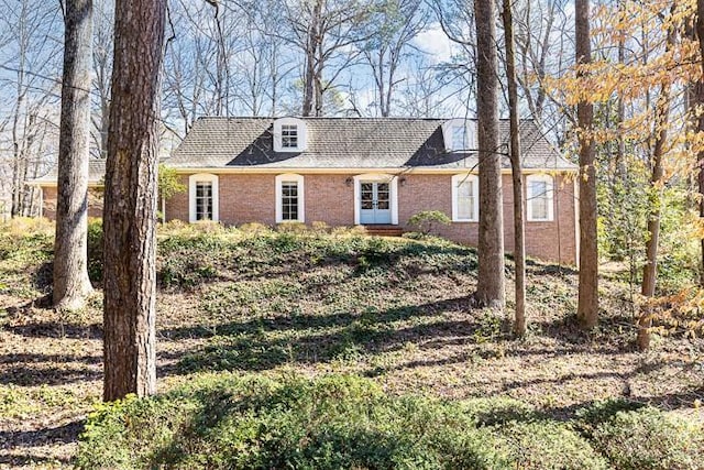 cape cod home featuring brick siding