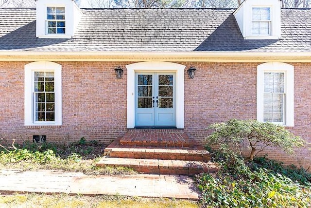 property entrance featuring a shingled roof, french doors, and brick siding