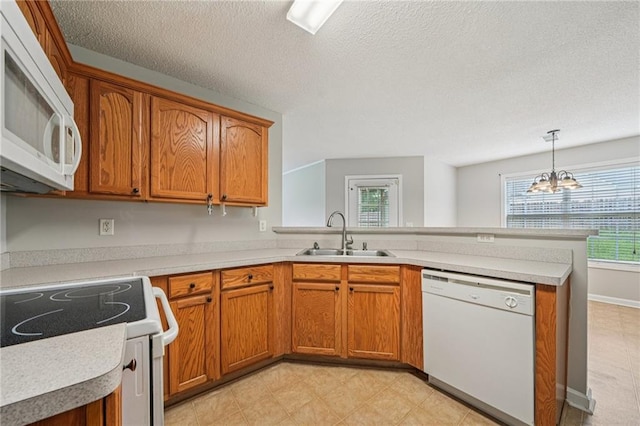 237 Raventree Ln, Griffin, GA 30224 - kitchen with white appliances, a peninsula, brown cabinets, light countertops, and a chandelier