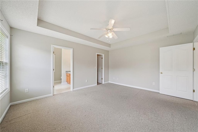 237 Raventree Ln, Griffin, GA 30224 - unfurnished bedroom with multiple windows, carpet, a textured ceiling, a tray ceiling, and ensuite bath