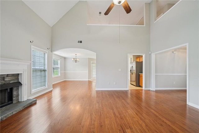 237 Raventree Ln, Griffin, GA 30224 - unfurnished living room with a ceiling fan, a stone fireplace, high vaulted ceiling, wood finished floors, and arched walkways