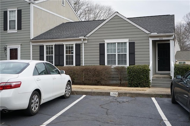 view of front of home featuring uncovered parking and roof with shingles