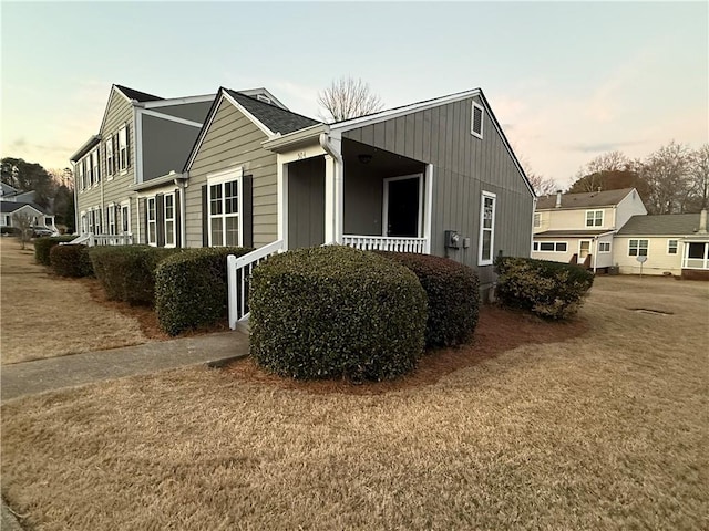 view of side of home featuring a yard and a porch