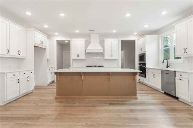 kitchen featuring light wood finished floors, custom range hood, a kitchen island, a breakfast bar, and stainless steel appliances