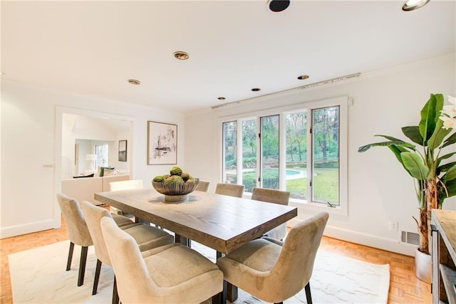 dining space featuring light parquet floors and ornamental molding