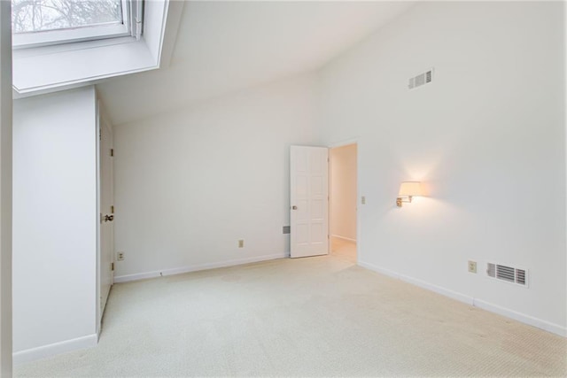 spare room featuring light colored carpet and high vaulted ceiling