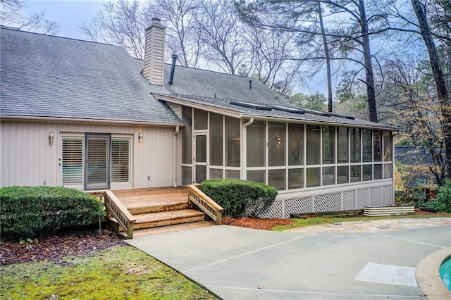 rear view of house with a wooden deck, a patio, and a sunroom