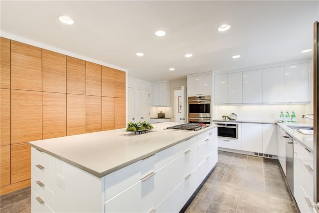 kitchen with white cabinetry, sink, stainless steel appliances, tile patterned floors, and a spacious island