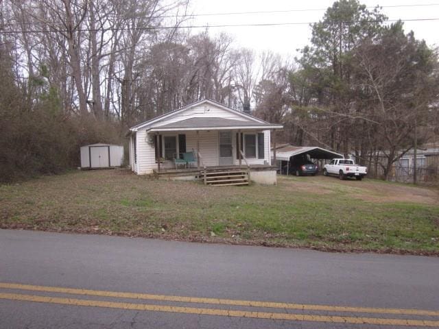 view of front of house with a shed, a front lawn, a carport, and a porch