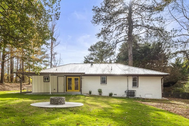 back of property with a lawn, french doors, and an outdoor fire pit