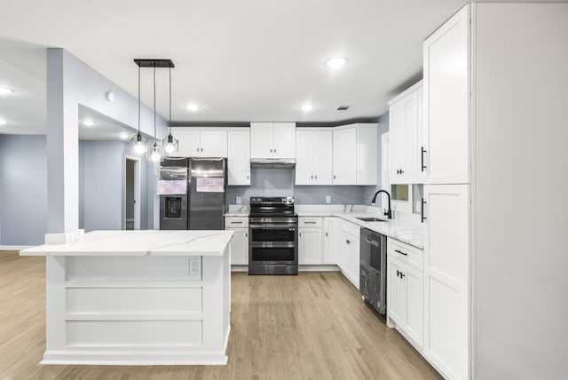 kitchen featuring pendant lighting, light wood-type flooring, a kitchen island, white cabinetry, and stainless steel appliances