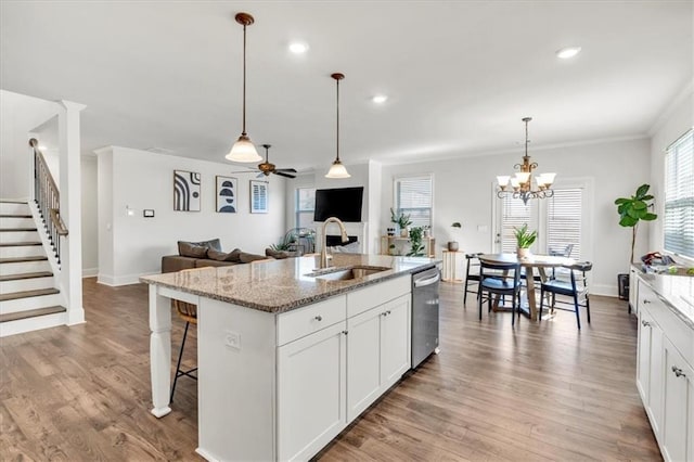 kitchen with a sink, light stone counters, light wood-style floors, and dishwasher