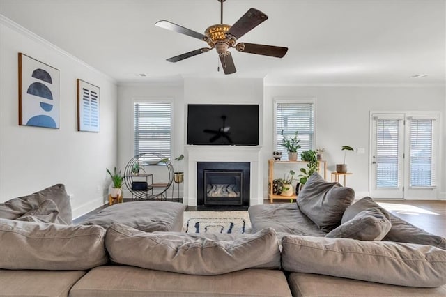 living area featuring a fireplace with flush hearth, plenty of natural light, and ornamental molding