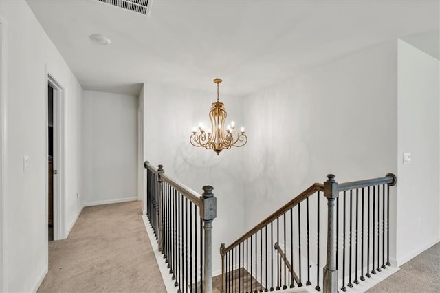 stairs featuring a chandelier, visible vents, baseboards, and carpet floors