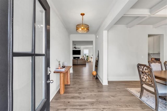 entryway featuring beamed ceiling, a notable chandelier, light wood-style floors, crown molding, and baseboards