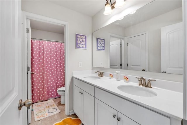 bathroom featuring double vanity, toilet, and a sink