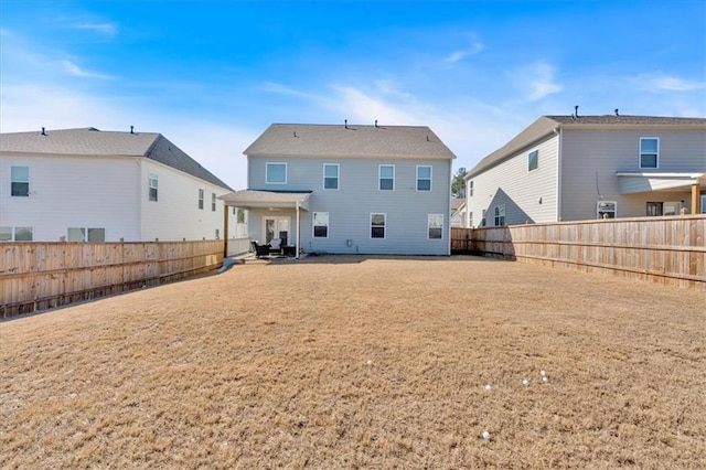 rear view of house with a patio, a lawn, and a fenced backyard