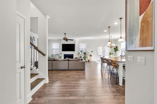 living area featuring stairway, a healthy amount of sunlight, wood finished floors, and a fireplace