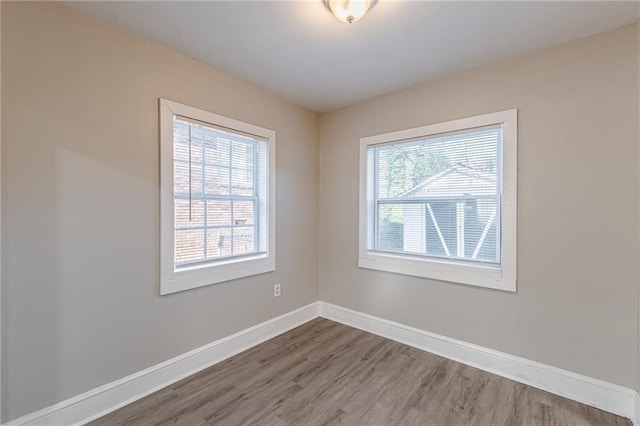 empty room with a healthy amount of sunlight, baseboards, and wood finished floors