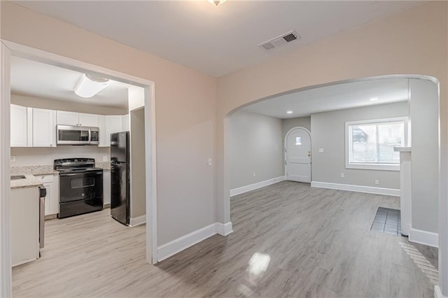 kitchen featuring arched walkways, visible vents, white cabinetry, light wood-type flooring, and black appliances