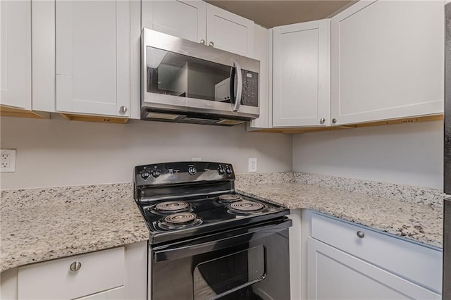 kitchen with black range with electric cooktop, white cabinets, stainless steel microwave, and light stone countertops