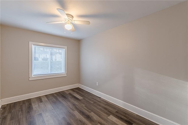 spare room featuring dark wood-style flooring, ceiling fan, and baseboards