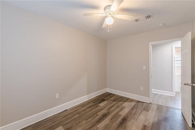 empty room with a ceiling fan, wood finished floors, visible vents, and baseboards