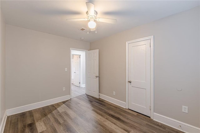 empty room with a ceiling fan, wood finished floors, visible vents, and baseboards