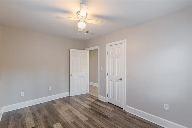 unfurnished bedroom featuring dark wood-style flooring, visible vents, and baseboards