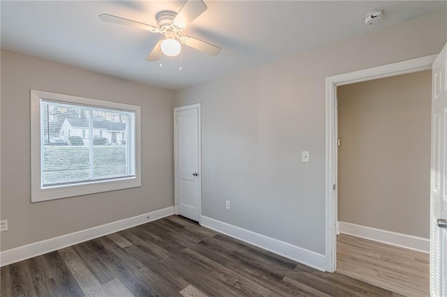 unfurnished room featuring a ceiling fan, dark wood-style flooring, and baseboards