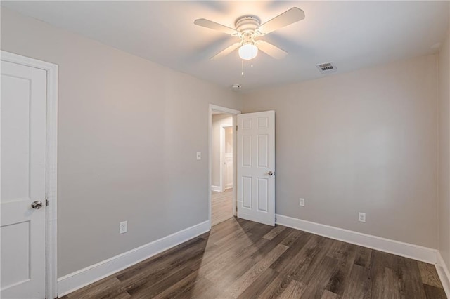 spare room featuring ceiling fan, dark wood finished floors, visible vents, and baseboards