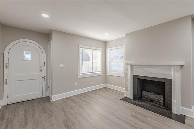 foyer entrance featuring recessed lighting, baseboards, a tiled fireplace, and wood finished floors