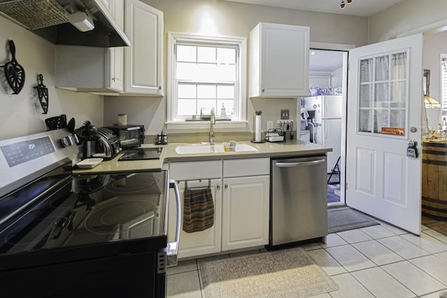 kitchen with light tile patterned floors, appliances with stainless steel finishes, sink, and white cabinets