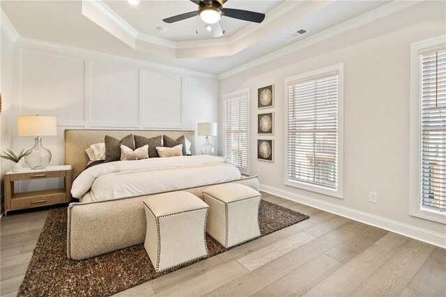 235 Briscoe Way Unit 7, Alpharetta, GA 30009 - bedroom featuring visible vents, a tray ceiling, hardwood / wood-style flooring, crown molding, and a decorative wall