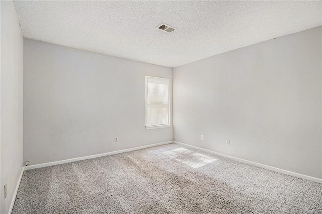 carpeted empty room with a textured ceiling, visible vents, and baseboards