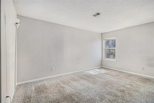 unfurnished room with a textured ceiling, carpet floors, visible vents, and baseboards