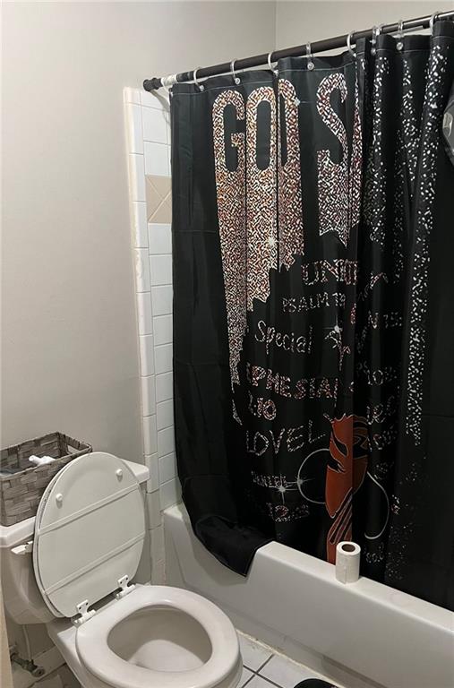 bathroom with tile patterned flooring, toilet, and shower / bath combo with shower curtain